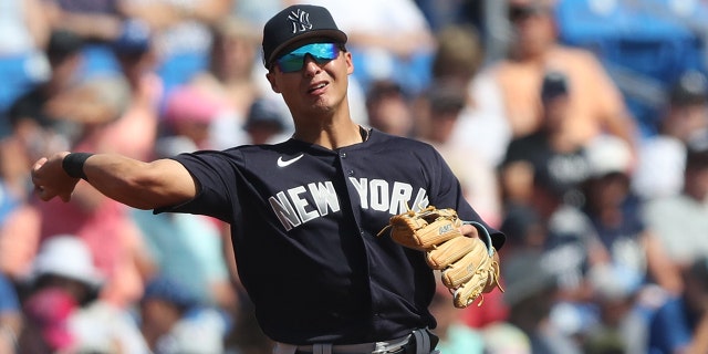 New York Yankees iç saha oyuncusu Anthony Volpe (77), 26 Şubat 2023'te Dunedin, FL'deki TD Ballpark'ta New York Yankees ile Toronto Blue Jays arasındaki bir bahar antrenman maçında topu ilk kaleye atıyor.