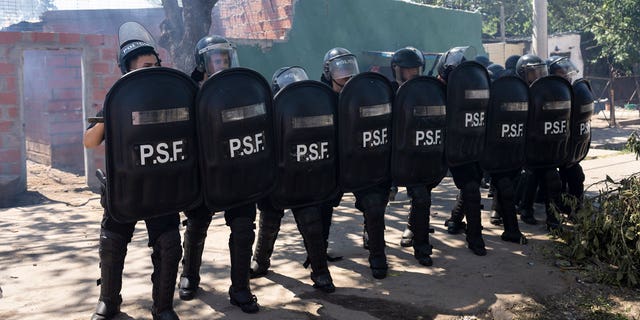 Police in riot gear stand by after the burial of Máximo Jerez, an 11-year-old boy killed in the crossfire of a shooting in the Los Pumitas neighborhood of Rosario, Argentina on March 6, 2023.