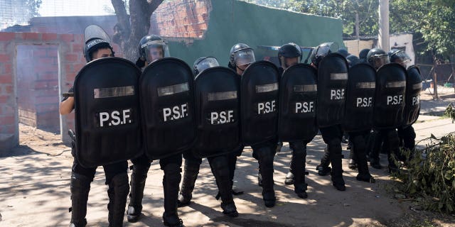 Police in riot gear stand by after the burial of Máximo Jerez, an 11-year-old boy killed in the crossfire of a shooting in the Los Pumitas neighborhood of Rosario, Argentina on March 6, 2023.