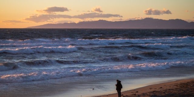 A lone person stands on the shore near the Manhattan Beach Pier, in Manhattan Beach, California, March 1, 2023. 