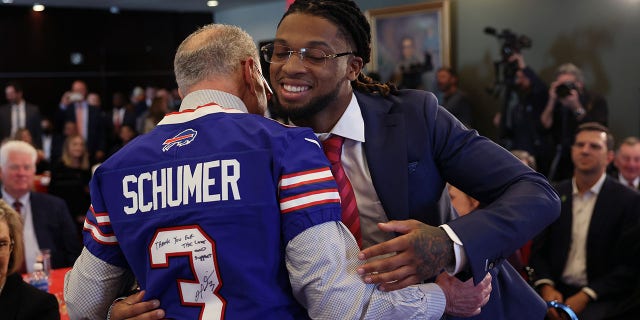 Senate Majority Leader Charles Schumer, left, greets Buffalo Bills security Damar Hamlin at an event to introduce the AED Access Act on March 29, 2023 in Washington, DC