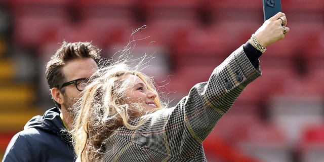 Wrexham co-owner Ryan Reynolds has his photo taken by his wife Blake Lively before a Vanarama National League match between Wrexham and York City at the Racecourse Ground on March 25, 2023, in Wrexham, Wales.