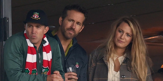 Wrexham owners Rob McElhinney and Ryan Reynolds and Reynolds' wife Blake Lively watch a Vanarama National League match between Wrexham and York City at the Racecourse Ground on March 25, 2023 in Wrexham, Wales.
