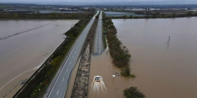 A CalTrans vehicle drives north through floodwaters that closed state Highway 1 at the Santa Cruz County line, in California, on March 12, 2023.