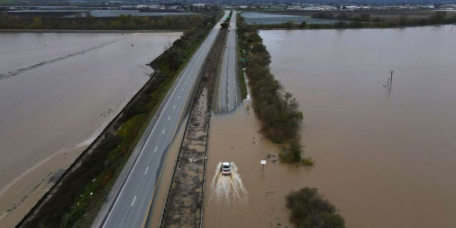 A CalTrans vehicle drives north through floodwaters that closed state Highway 1 at the Santa Cruz County line, in California, on March 12, 2023.