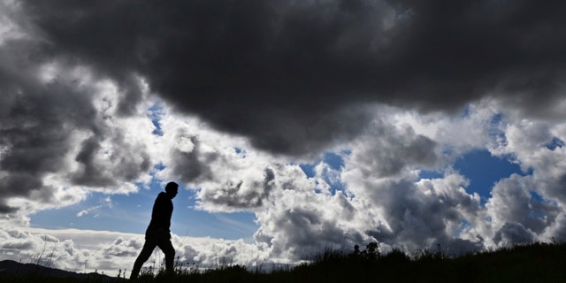 Gabriel Gonzalez, of San Rafael, walks up a hillside as storm clouds approach from the west in Walnut Creek, Calif., on March 13, 2023. 