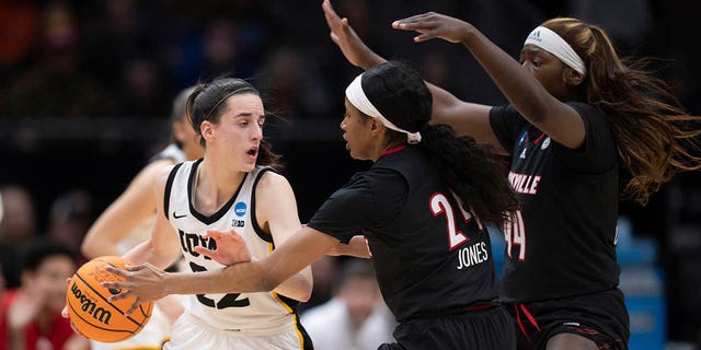 Iowa guard Caitlin Clark, left, looks to pass the ball against Louisville guard Morgan Jones, center, and forward Olivia Cochran during the first half of the NCAA Tournament Elite 8 college basketball game, Sunday, March 26, 2023, in Seattle.