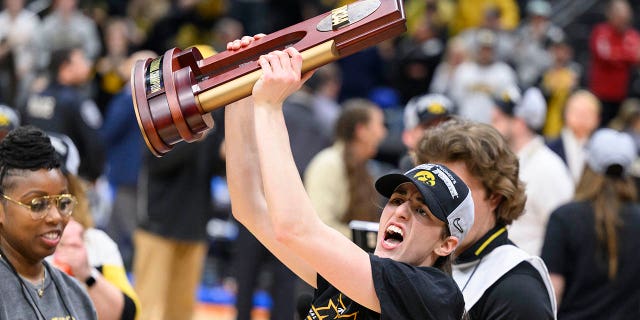 Iowa guard Caitlin Clark shows off the trophy as she celebrates after an Elite 8 college basketball game of the NCAA Tournament against Louisville, Sunday, March 26, 2023, in Seattle.