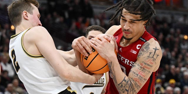 Caleb McConnell, #22 of the Rutgers Scarlet Knights, and Fletcher Loyer, #2 of the Purdue Boilermakers, fight for the basketball during the second half of the Big Ten Tournament quarterfinals at the United Center on March 10, 2023 in Chicago.