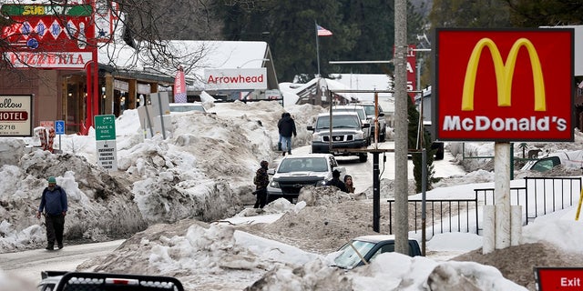 People walk along a plowed street in Crestline, California, March 6 after a series of winter storms dropped more than 100 inches of snow in the San Bernardino Mountains in Southern California.