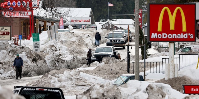 People walk along a plowed street in Crestline, California, March 6 after a series of winter storms dropped more than 100 inches of snow in the San Bernardino Mountains in Southern California.