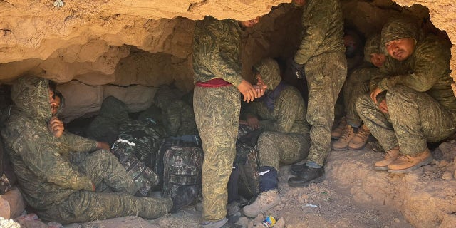 Three dozen illegal immigrants decked in camouflage while hiding in a cave in the desert.