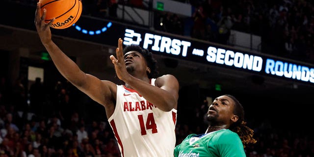 Alabama center Charles Bediako (14) lays in a basket as Texas A&amp;M Corpus Christi forward De'Lazarus Keys (13) defends in the first half of a first-round college basketball game in the NCAA Tournament in Birmingham, Ala., Thursday, March 16, 2023. 