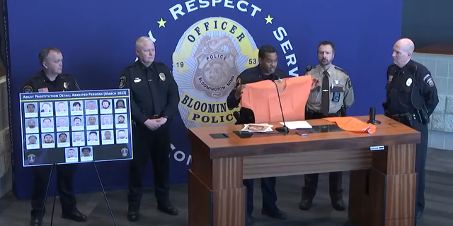 Bloomington Police Chief Booker Hodges holds up an orange jumpsuit after prostitution sting.