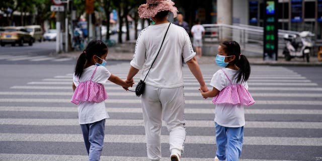 A mother walks with her twin daughters on a street in Shanghai, China, on June 7, 2021.