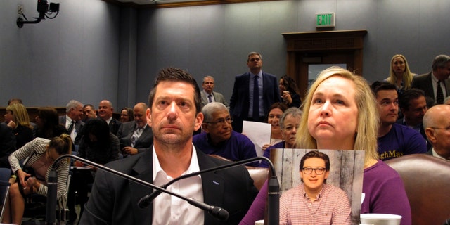 From left to right, Stephen and Rae Ann Gruver sit in a House committee room behind a photo of their son, 18-year-old Maxwell Gruver, a Louisiana State University freshman who died with a blood-alcohol content six times higher than the legal limit for driving in what authorities say was a hazing incident, in Baton Rouge, Louisiana.