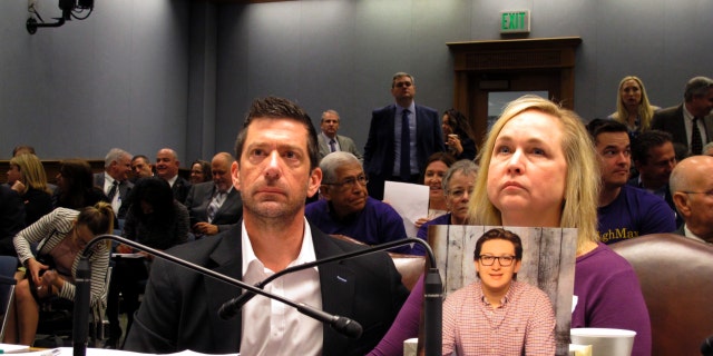 From left to right, Stephen and Rae Ann Gruver sit in a House committee room behind a photo of their son, 18-year-old Maxwell Gruver, a Louisiana State University freshman who died with a blood-alcohol content six times higher than the legal limit for driving in what authorities say was a hazing incident, in Baton Rouge, Louisiana.