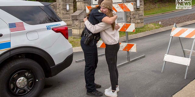 A police officer comforts a mourner outside of Covenant School in Nashville, Tennessee on Tuesday, March 28, 2023.  Six people - three adults and three children - were killed in a mass shooting at the school on Monday.