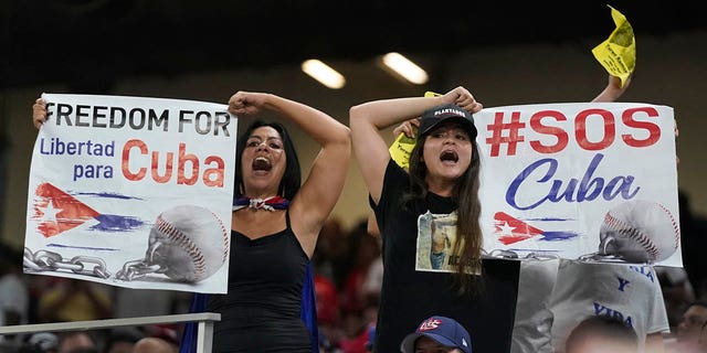 Los manifestantes sostienen carteles y cantan durante la sexta entrada de un juego del Clásico Mundial de Béisbol entre Cuba y Estados Unidos, el domingo 19 de marzo de 2023, en Miami.