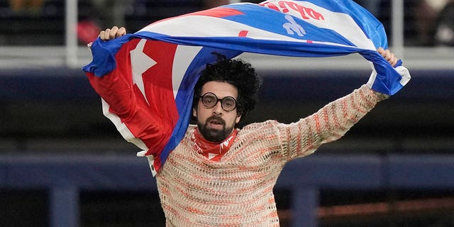 A protester runs on the field holding a Cuban flag during the eighth inning of a World Baseball Classic game between Cuba and U.S., Sunday, March 19, 2023, in Miami.