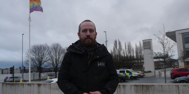 Dave McConnell outside the Elland Road Police Station where he was detained, which flies an LGBTQ flag.