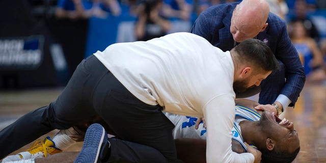 UCLA guard David Singleton yells while being treated by the team trainer, as coach Mick Cronin joins them, during the second half of the team's second-round college basketball game against Northwestern in the men's NCAA Tournament, Saturday, March 18, 2023, in Sacramento, Calif.