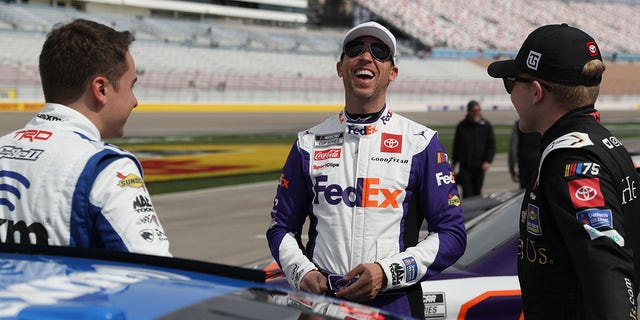Denny Hamlin, driver of the #11 FedEx Express Toyota, (C) shares a laugh with Christopher Bell, driver of the #20 SiriusXM Toyota, (L) and Ty Gibbs, driver of the #54 He Get us Toyota, on the grid during practice for the NASCAR Cup Series Pennzoil 400 at Las Vegas Motor Speedway on March 04, 2023 in Las Vegas, Nevada. 