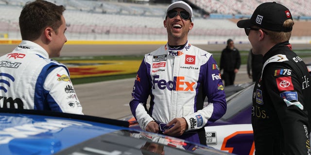 Denny Hamlin, driver of the #11 Toyota FedEx Express, (C) laughs with Christopher Bell, driver of the #20 Toyota SiriusXM, (L) and Ty Gibbs, driver of the #54 Toyota He Get us, at the grid during practice for the NASCAR Cup Series Pennzoil 400 at Las Vegas Motor Speedway on March 4, 2023 in Las Vegas, Nevada. 