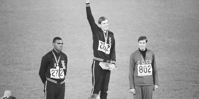 FILE - Gold medalist Dick Fosbury raises his arm on the victor's podium of the Olympic stadium, Oct. 20, 1968, in Mexico City.