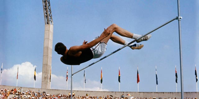 American high jumper Dick Fosbury clears the bar on his third attempt at the 1968 Summer Games in Mexico City. Fosbury won the gold medal with this jump, clearing 7 feet, 4 1/4 inches, which also set Olympic and American records.