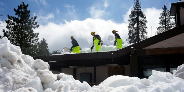 Members of the Cal Fire Crew clear snow from the roof of the city's post office following a series of storms on Wednesday, March 8, 2023 in Crestline, Calif.