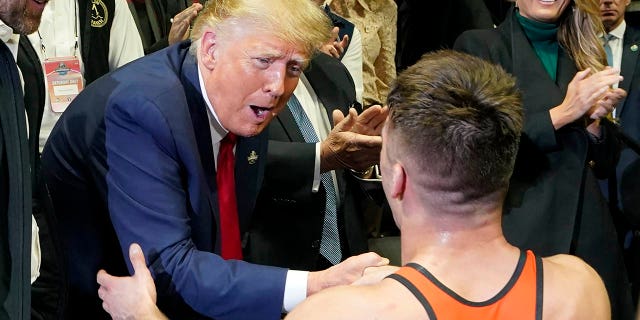 El expresidente Donald Trump, a la izquierda, felicita al luchador de Princeton Pat Glory después de que Glory ganara el campeonato de lucha libre de la NCAA en la clase de 125 libras, el sábado 18 de marzo de 2023 en Tulsa, Oklahoma.