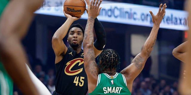 Cleveland Cavaliers guard Donovan Mitchell, #45, shoots a 3-point basket against Boston Celtics guard Marcus Smart, #36, during the first half of an NBA basketball game, Monday, March 6, 2023, in Cleveland.