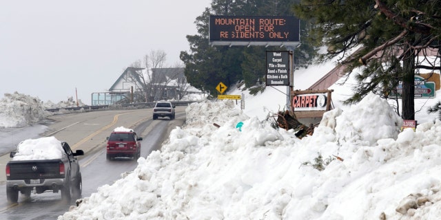 Mounds of snow cover the sides of the main road leading out of the mountains after a series of storms Wednesday, March 8, 2023, in Lake Arrowhead. Californians are still struggling to dig out and get necessities in the aftermath of a record-setting blizzard last month.