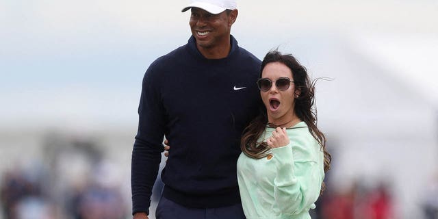 Tiger Woods poses with Erica Herman during a practice.
