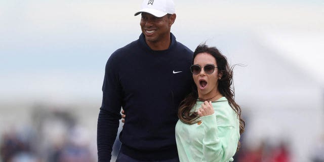 Tiger Woods poses with Erica Herman during a practice.