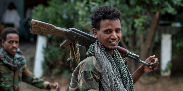 Fighters loyal to the Tigray People's Liberation Front (TPLF) walk along a street in the town of Hawzen, then controlled by the group, in the Tigray region of northern Ethiopia on May 7, 2021.