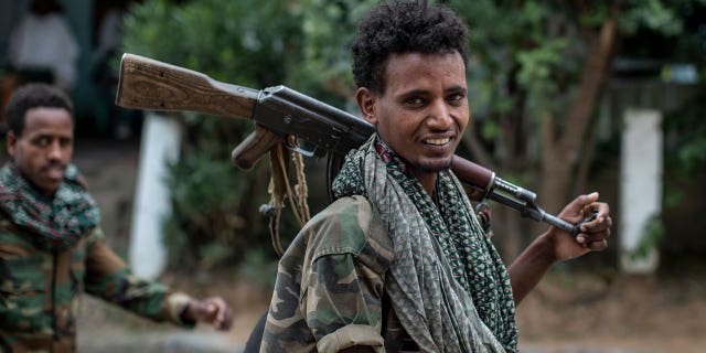 Fighters loyal to the Tigray People's Liberation Front (TPLF) walk along a street in the town of Hawzen, then controlled by the group, in the Tigray region of northern Ethiopia on May 7, 2021.