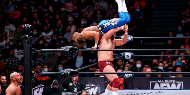Brock Anderson flips Lee Johnson over the top rope and on to Dax Harwood during the AEW Dynamite - Beach Break taping on January 26, 2022, at the Wolstein Center in Cleveland, OH.