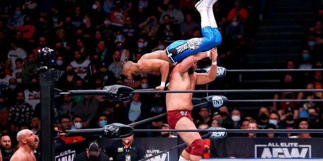 Brock Anderson flips Lee Johnson over the top rope and on to Dax Harwood during the AEW Dynamite - Beach Break taping on January 26, 2022, at the Wolstein Center in Cleveland, OH.