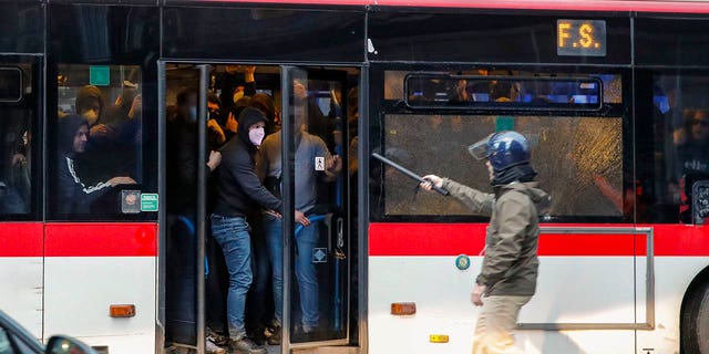 Aficionados del equipo de fútbol Eitracht Frankfurt son sometidos y llevados en un autobús después de un enfrentamiento con la policía el miércoles 15 de marzo de 2023 en Nápoles, Italia, donde su equipo se prepara para jugar un partido de vuelta de los octavos de final de la Liga de Campeones contra Napoli .