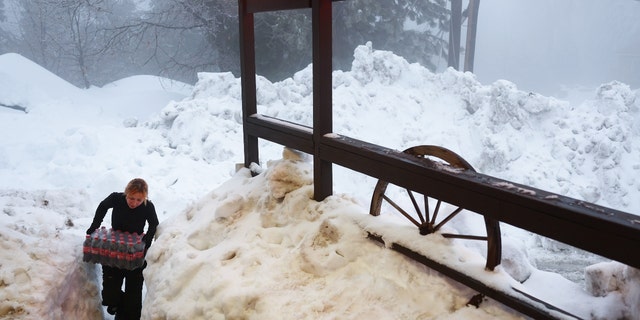 Resident Jessica Neakarse helps re-stock Mountain High Market after a series of winter storms dropped more than 100 inches of snow in the San Bernardino Mountains in Southern California on March 6, 2023, in Twin Peaks, California. 