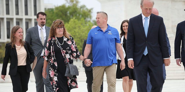 Former Bremerton High School assistant football coach Joe Kennedy holds hands with his wife Denise as he walks in front of the US Supreme Court with members of his legal team after their case, Kennedy v. Bremerton school district, will appear in the Supreme Court on April 25.  , 2022 in Washington, DC.