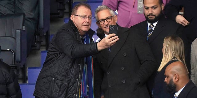 Soccer broadcaster Gary Lineker, centre right, poses for photographs with a fan in the stands, ahead of the English Premier League soccer match between Leicester City and Chelsea at the King Power Stadium, in Leicester, England, Saturday March 11, 2023.