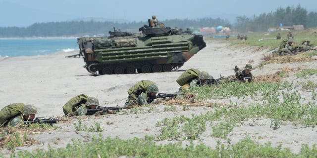 Philippine marines take position next to U.S. Marines amphibious assault vehicles during an amphibious landing exercise at the beach of the Philippine navy training center facing the south China sea in San Antonio town, Zambales Province.