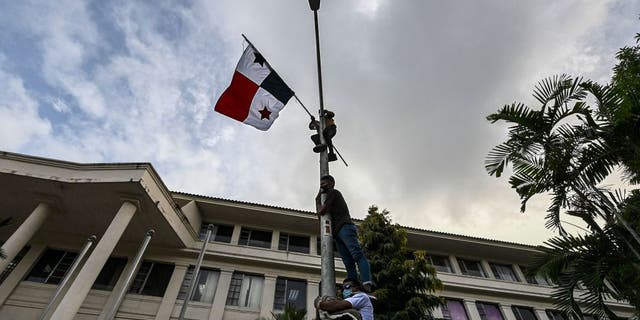 Men climb up a light pole with a Panamanian flag during a protest against same-sex marriage, outside the Supreme Court of Justice, in Panama City, on October 07, 2020. - Protesters demanded Supreme Court magistrates not to accept a claim of unconstitutionality against article 26 of the Family Code, which only recognizes the union between a man and a woman.