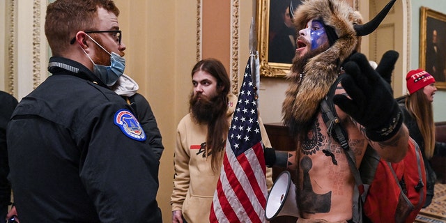 US Capitol police officers try to stop supporters of US President Donald Trump, including Jake Angeli, R, a QAnon supporter known for his painted face and horned hat, to enter the Capitol on January 6, 2021, in Washington, DC. 