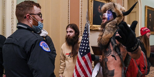 US Capitol police officers try to stop supporters of US President Donald Trump, including Jake Angeli, R, a QAnon supporter known for his painted face and horned hat, to enter the Capitol on January 6, 2021, in Washington, DC.