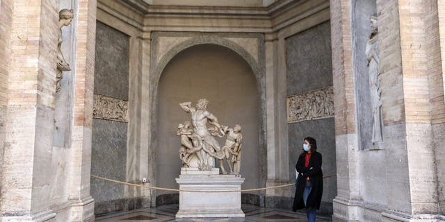 A visitor looks at the "Laocoon and his sons" sculpture in the Vatican Museums.
