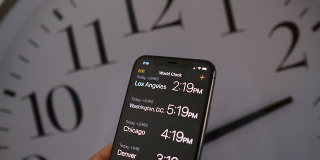 Foto ilustrasi ini memperlihatkan jam di latar belakang ponsel cerdas yang menunjukkan waktu setelah waktu musim panas diterapkan di Los Angeles, California, pada 15 Maret 2022.